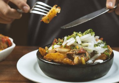 Man eating Beef stew with potatoes, carrots and herbs on black background with copy