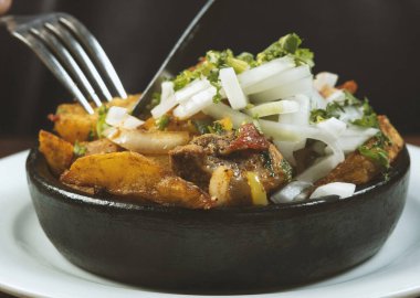 Man eating Beef stew with potatoes, carrots and herbs on black background with copy