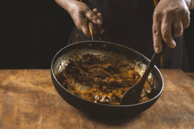 Aşçı eti sebzeli ve soğanlı bir kasede hazırlar. Doğu mutfağı.