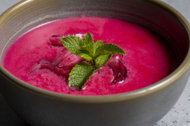 Cold beetroot soup with mint in a bowl on a gray background