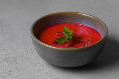 Cold beetroot soup with mint in a bowl on a gray background