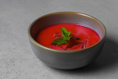 Cold beetroot soup with mint in a bowl on a gray background