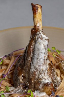 Lamb chop with noodles, sauce and mustard on a gray background