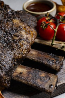 grilled pork ribs with french fries and vegetables on a wooden board