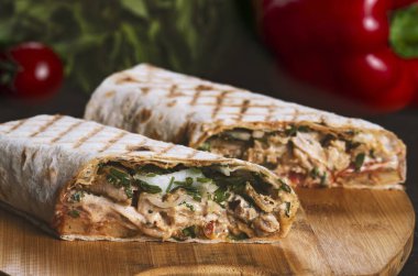 Shawarma sandviçi taze rulo, ızgara et ve siyah arka planda beyaz soslu salata..