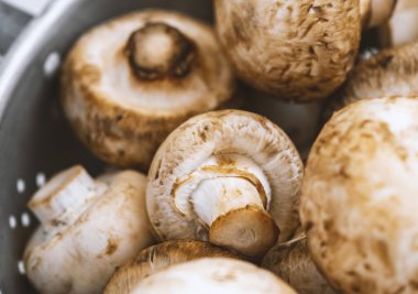 Beyaz ahşap arka planda demir bir kasede çiğ mantar.