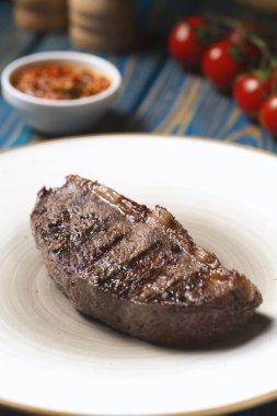 Izgara biftek, kiraz domatesleri ahşap masada tuz ve biber..