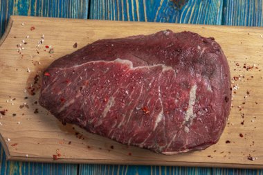 Tahtada çiğ et ve ahşap arka planda baharatlar.