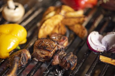 Kızarmış et ve sebzeler alevler ve sebzelerle ızgarada, yakın çekim.
