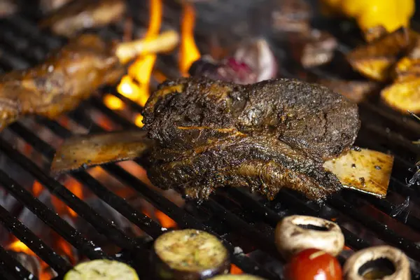 roasted meat and vegetables on the grill with flames and vegetables, close up