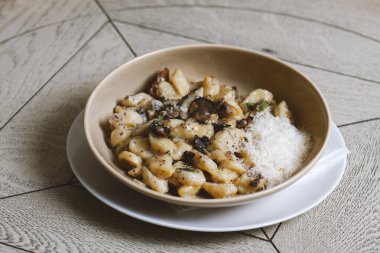 Mantarlı pappardelle makarna ve parmesan peyniri tabakta. Geleneksel İtalyan gnocchi makarna, mantarlı ve parmesan peynirli.