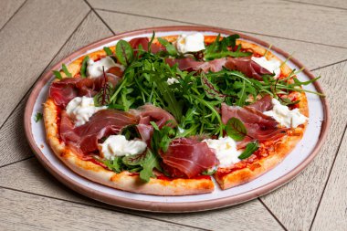 Prosciutto, roka ve peynirli pizza.