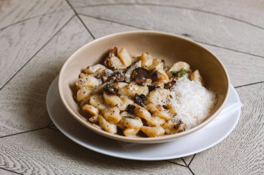 Mantarlı pappardelle makarna ve parmesan peyniri tabakta. Geleneksel İtalyan gnocchi makarna, mantarlı ve parmesan peynirli.