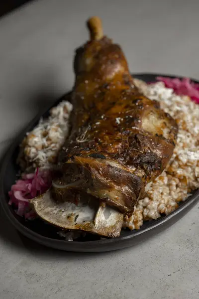 Leg of lamb with rice and red onion on gray background