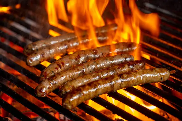 Grilling sausages on the grill with flames and smoke.