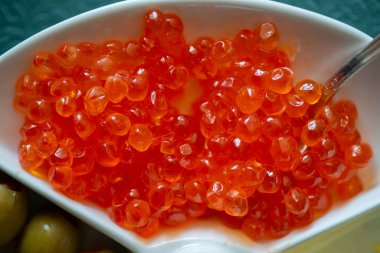 Beyaz bir tabakta kırmızı havyar Zeytin, peynir ve kaşık