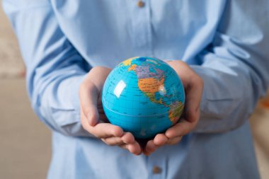 Elinde bir küre tutan adamın yakın çekimi. Bireyin gezegenin refahı için bakımı kavramı.