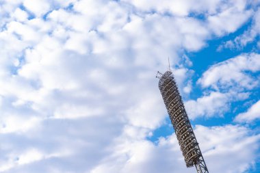 Açık mavi gökyüzünde spor stadyumunun ışıklandırma sistemi. Stadyum ışıkları