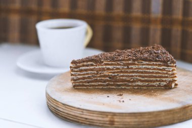 Tahta tabakta bir parça çikolatalı kek ve bir fincan kahve.