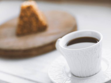 Bir fincan kahve ve tahtanın üzerinde bir parça kek.