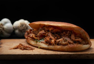 Shawarma ve sarımsak ahşap masada, siyah arka planda.
