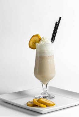 Muzlu milkshake, beyaz bir tabakta muz parçalarıyla birlikte dondurmalı dondurma..