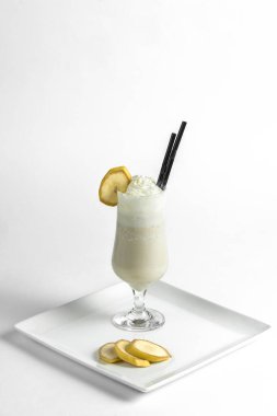 Muzlu milkshake, beyaz bir tabakta muz parçalarıyla birlikte dondurmalı dondurma..