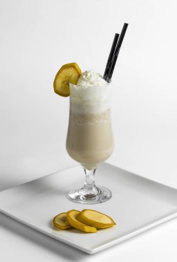 Muzlu milkshake, beyaz bir tabakta muz parçalarıyla birlikte dondurmalı dondurma..