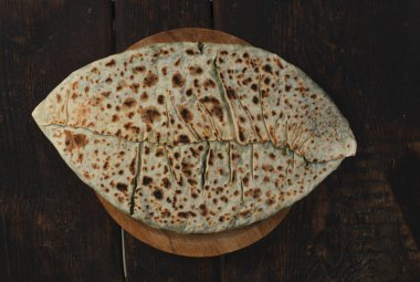 Ahşap tahtada otlu ve peynirli geleneksel turta.