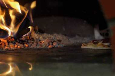 Yanan bir fırında pişen lezzetli pizzanın yakın çekimi.