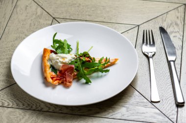 Somon füme pizza ve beyaz tabakta roka.