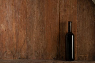 Şaraphanenin ahşap zemininde bir şişe kırmızı şarap.
