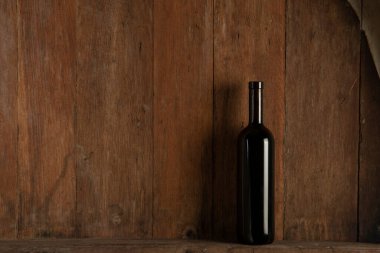 Şaraphanenin ahşap zemininde bir şişe kırmızı şarap.