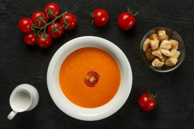 Siyah masada beyaz kasede domates kremalı çorba.