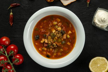 Siyah arka planda bir kase lezzetli solyanka sosis ve turşulu çorba. Yukarıdan görünüm