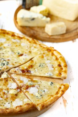 Tahta üzerinde dört peynirli pizza ve beyaz ahşap bir masada İtalyan pizzası için taze malzemeler. .