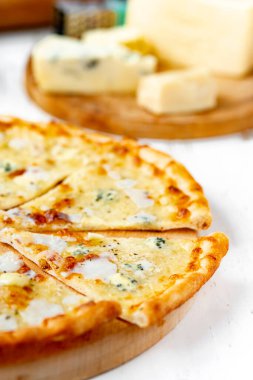 Tahta üzerinde dört peynirli pizza ve beyaz ahşap bir masada İtalyan pizzası için taze malzemeler. .