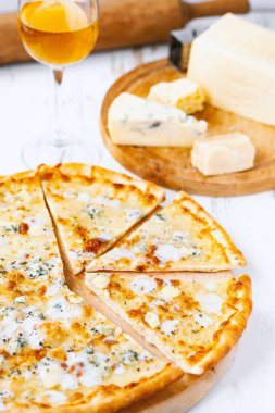 Tahta üzerinde dört peynirli pizza ve beyaz ahşap bir masada İtalyan pizzası için taze malzemeler. .