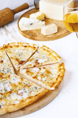 Tahta üzerinde dört peynirli pizza ve beyaz ahşap bir masada İtalyan pizzası için taze malzemeler. .