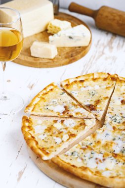 Tahta üzerinde dört peynirli pizza ve beyaz ahşap bir masada İtalyan pizzası için taze malzemeler. .