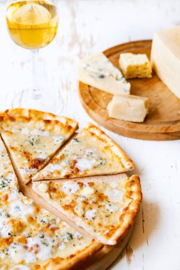 Tahta üzerinde dört peynirli pizza ve beyaz ahşap bir masada İtalyan pizzası için taze malzemeler. .