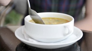 Restoranda terasta oturmuş çorba içen bir kadın.