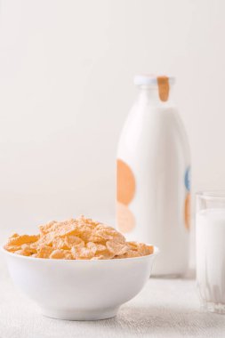 Bir kase mısır gevreği, sütlü, taze ahududu, yabanmersini. Sağlıklı kahvaltı için bir sürahi süt ve beyaz tahta üzerinde bir bardak.