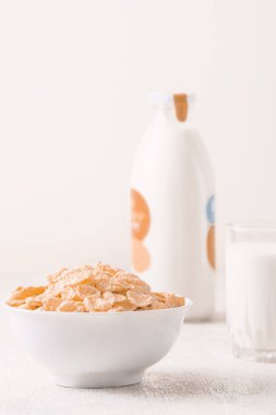 Bir kase mısır gevreği, sütlü, taze ahududu, yabanmersini. Sağlıklı kahvaltı için bir sürahi süt ve beyaz tahta üzerinde bir bardak.