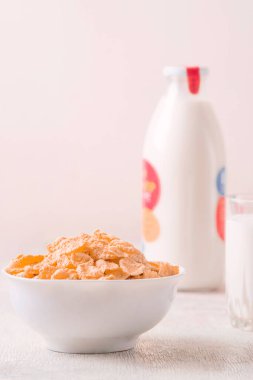 Bir kase mısır gevreği, sütlü, taze ahududu, yabanmersini. Sağlıklı kahvaltı için bir sürahi süt ve beyaz tahta üzerinde bir bardak.