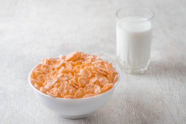 Bir kase mısır gevreği, sütlü, taze ahududu, yabanmersini. Sağlıklı kahvaltı için bir sürahi süt ve beyaz tahta üzerinde bir bardak.