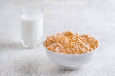 Bir kase mısır gevreği, sütlü, taze ahududu, yabanmersini. Sağlıklı kahvaltı için bir sürahi süt ve beyaz tahta üzerinde bir bardak.