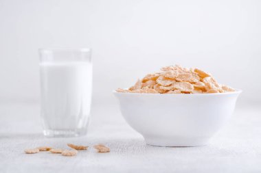 Bir kase mısır gevreği, sütlü, taze ahududu, yabanmersini. Sağlıklı kahvaltı için bir sürahi süt ve beyaz tahta üzerinde bir bardak.