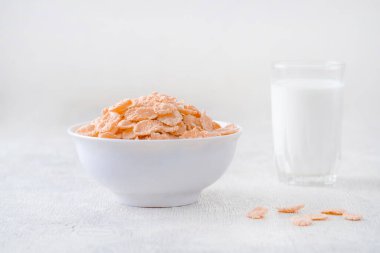 Bir kase mısır gevreği, sütlü, taze ahududu, yabanmersini. Sağlıklı kahvaltı için bir sürahi süt ve beyaz tahta üzerinde bir bardak.