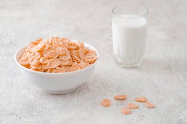 Bir kase mısır gevreği, sütlü, taze ahududu, yabanmersini. Sağlıklı kahvaltı için bir sürahi süt ve beyaz tahta üzerinde bir bardak.